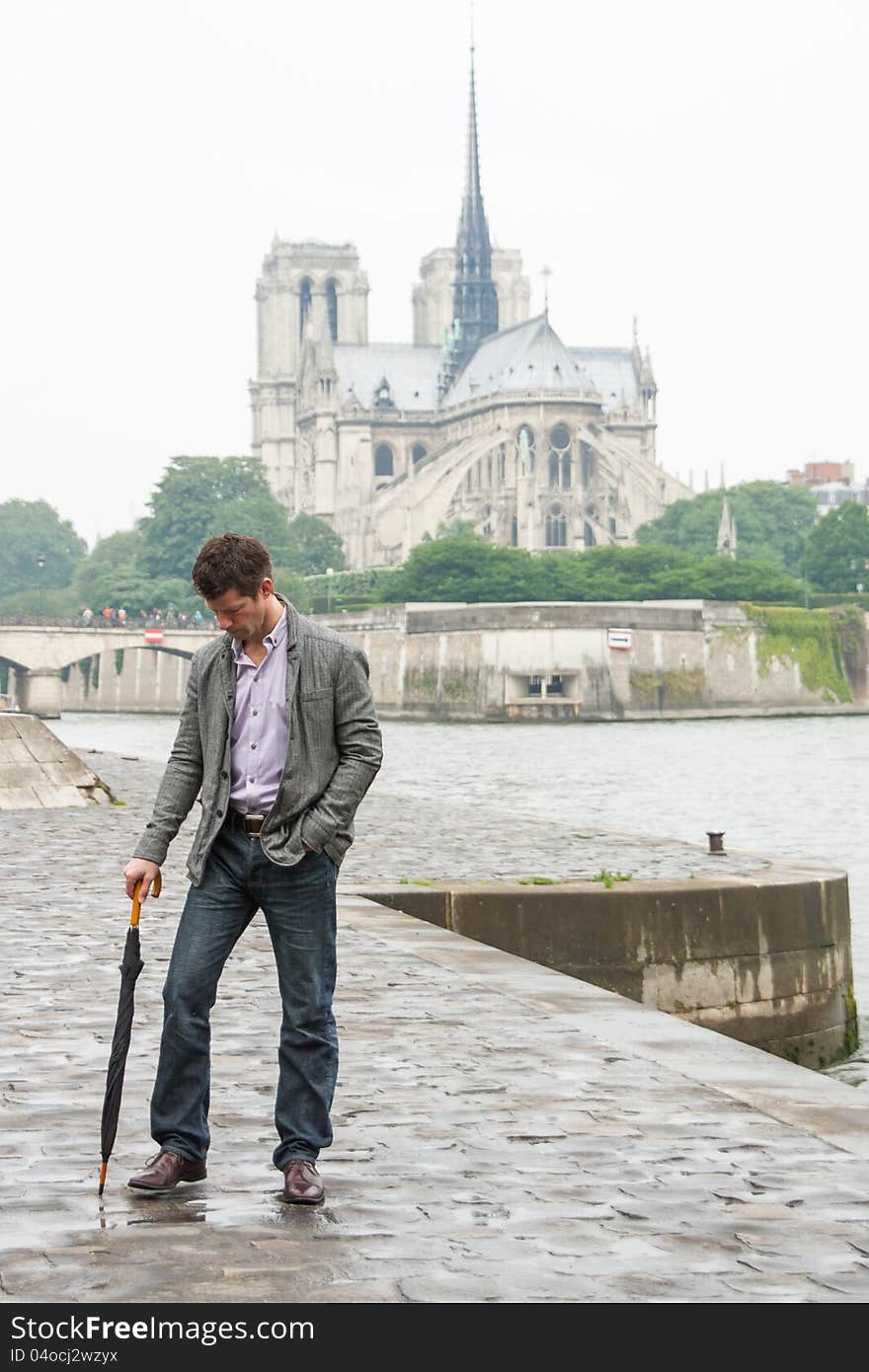 Sad man with an umbrella, standing in front of the Notre Dame Cathedral in Paris. Sad man with an umbrella, standing in front of the Notre Dame Cathedral in Paris.