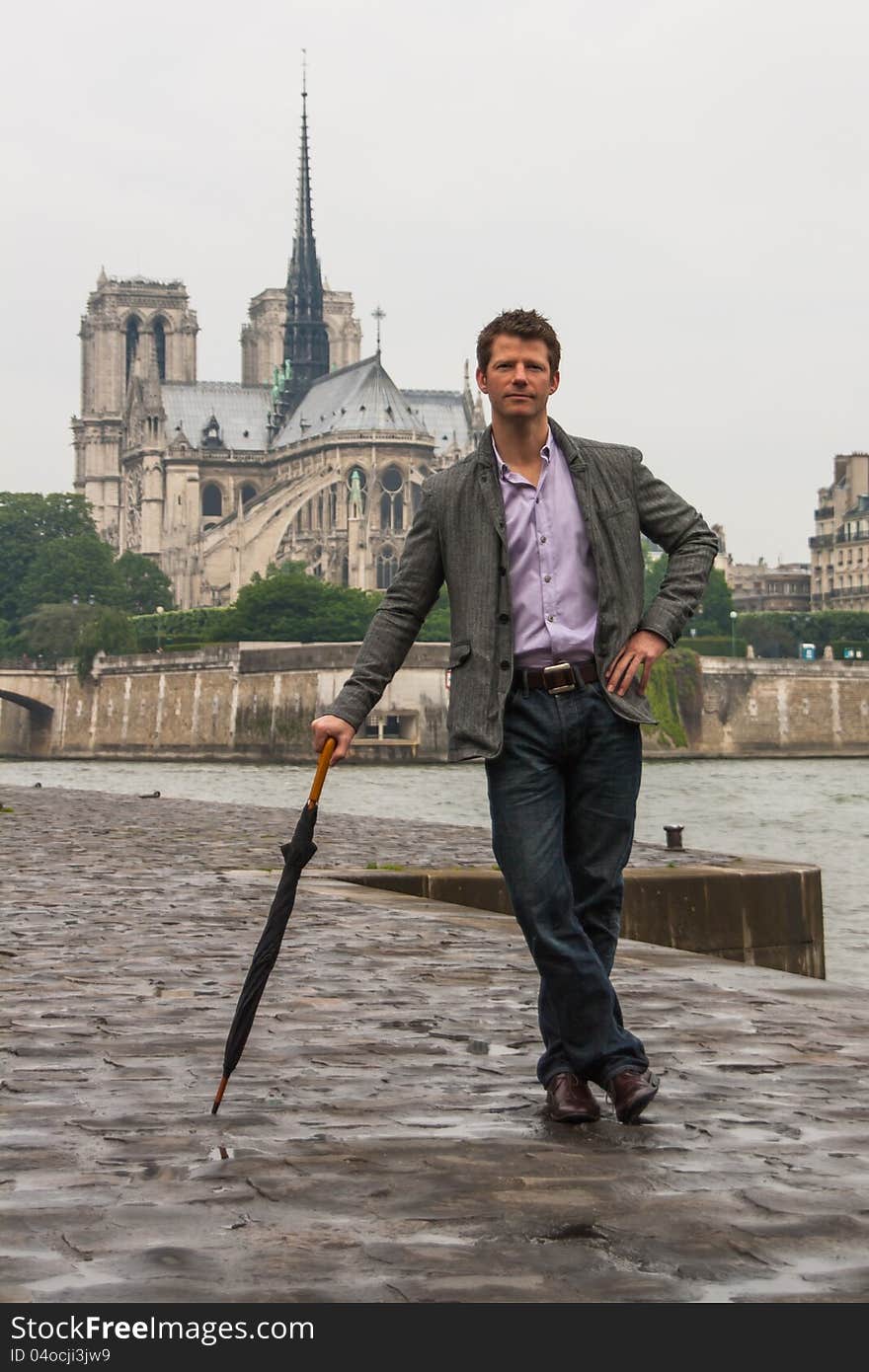 Solemn-lookin man, leaning on an umbrella, waiting in front of the Notre Dame Cathedral in Paris. Solemn-lookin man, leaning on an umbrella, waiting in front of the Notre Dame Cathedral in Paris.