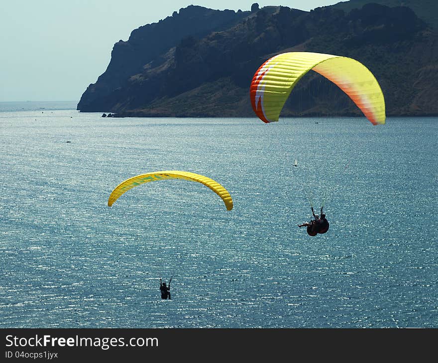 Paragliding in the blue sky above the sea and rocks