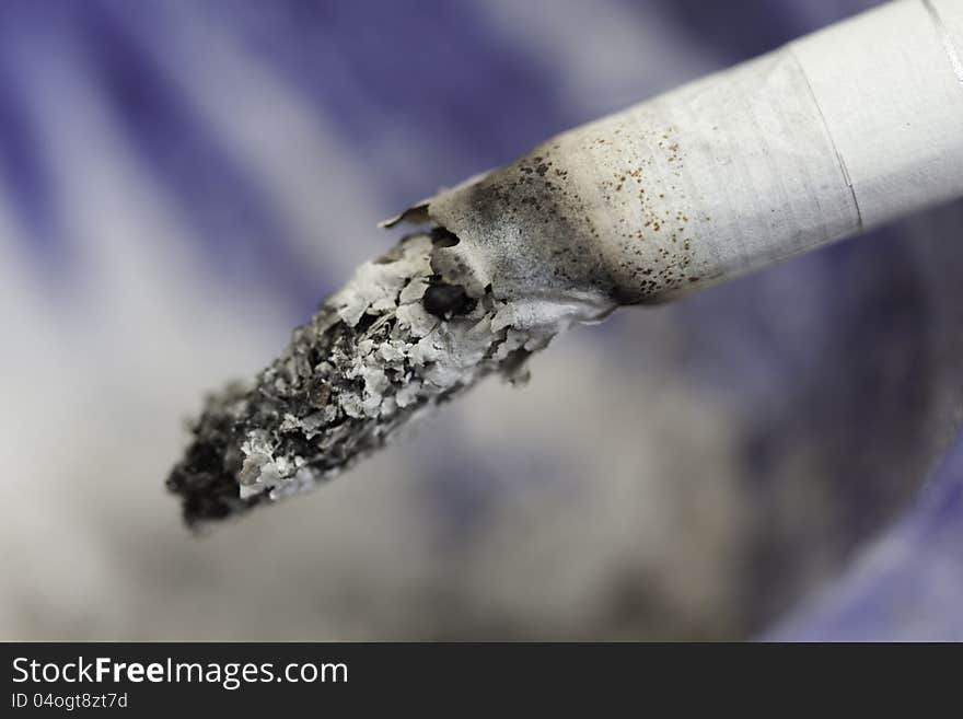 Close up of burning cigarette, on white and blue background. Close up of burning cigarette, on white and blue background