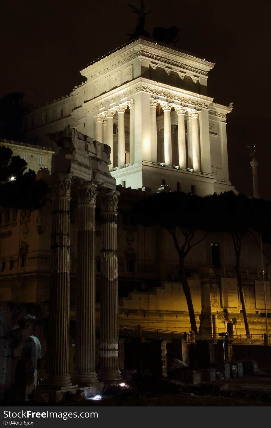 Monumento nazionale a vittorio emanuele II with the temple of vespasian in the foreground at night with black skies rome