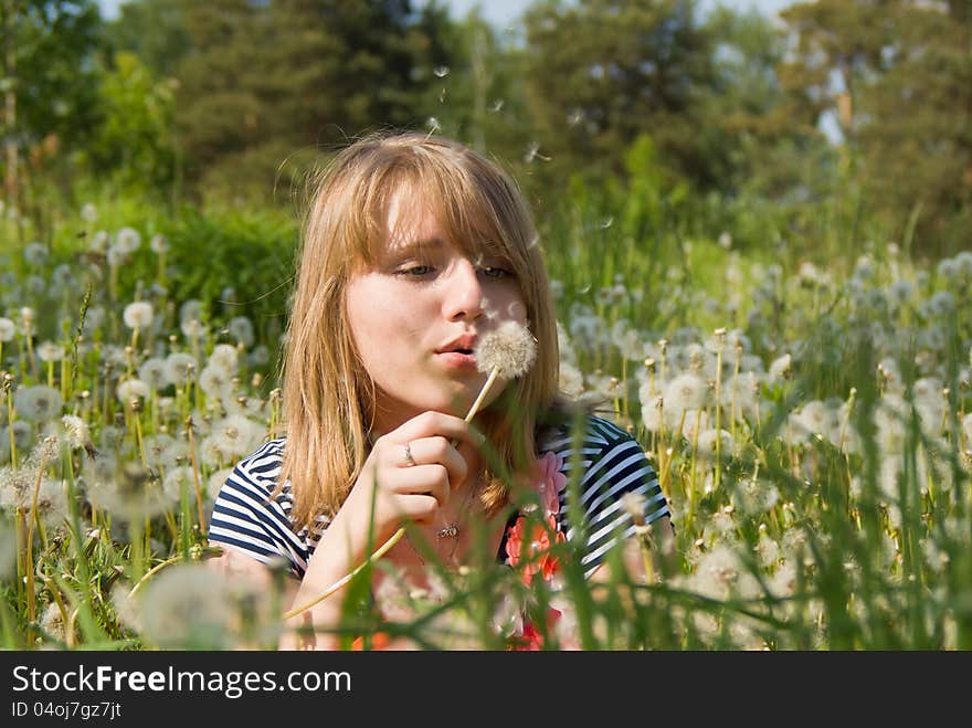 Beautiful girl blow on the dandelion on nature