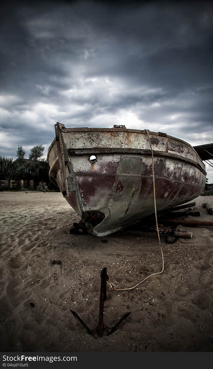 An old fishing boat on the beach. Stormy skies.