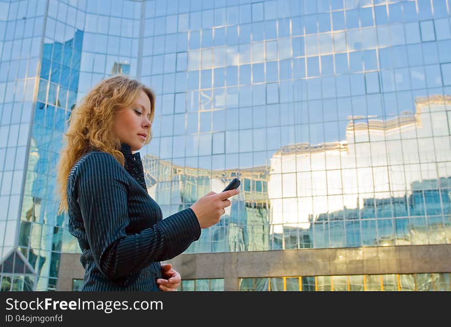 Young attractive businesswoman talking on mobile phone opposite office building