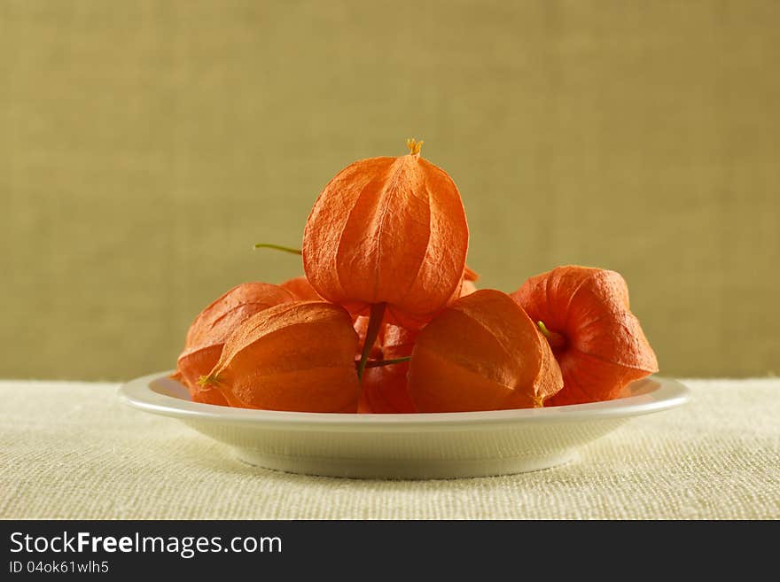 Heap of orange fruits on white plate with hard material on background. Heap of orange fruits on white plate with hard material on background