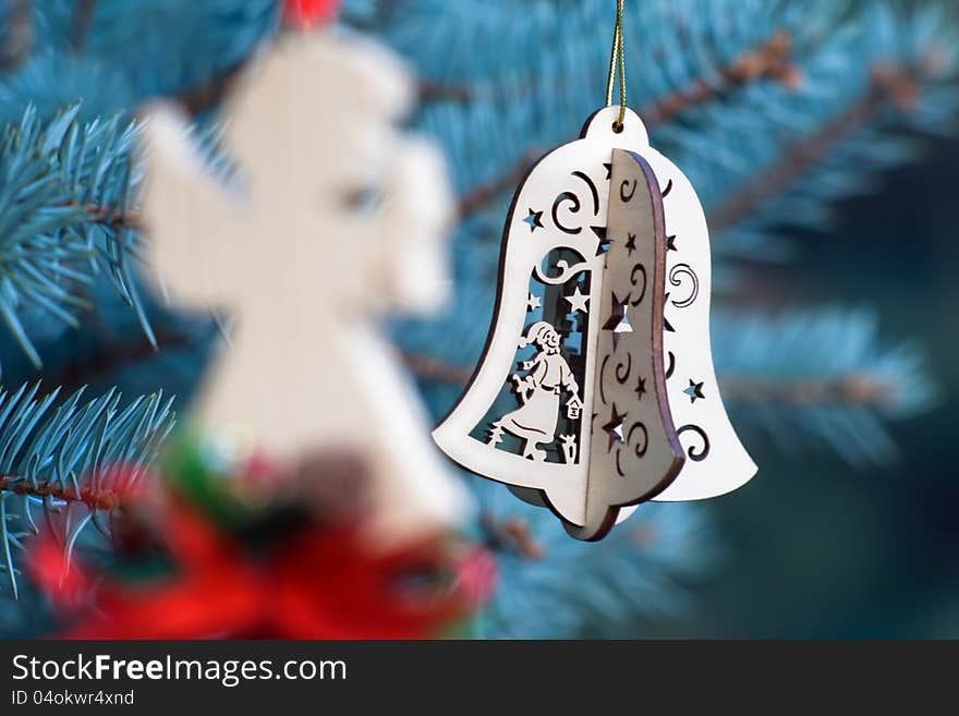 Christmas decoration of woody angel and handmade bell on the blue background of fir-tree. Christmas decoration of woody angel and handmade bell on the blue background of fir-tree