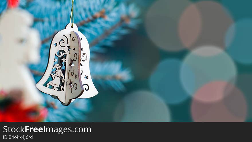 Christmas decoration of woody angel and handmade bell on the blue background of fir-tree having much space for text. Christmas decoration of woody angel and handmade bell on the blue background of fir-tree having much space for text