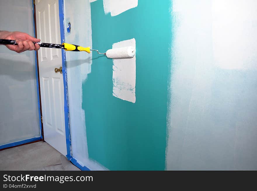 An image of a green wall being painted white