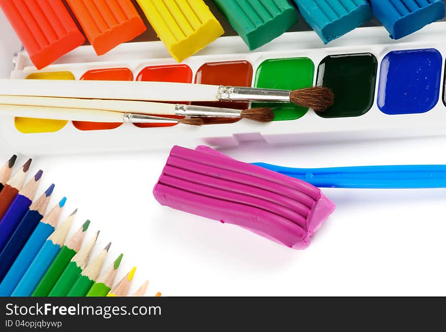 Arrangement of Clay, Paint Brushes, Color Pencils and Watercolor Paints isolated on white background. Arrangement of Clay, Paint Brushes, Color Pencils and Watercolor Paints isolated on white background