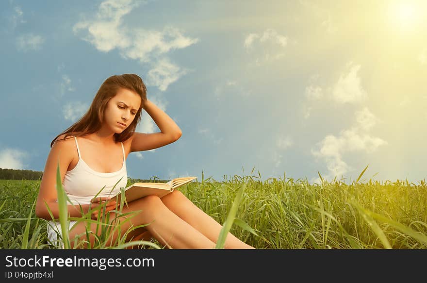 Beautiful girl student reading a book on the lawn in the park. Beautiful girl student reading a book on the lawn in the park