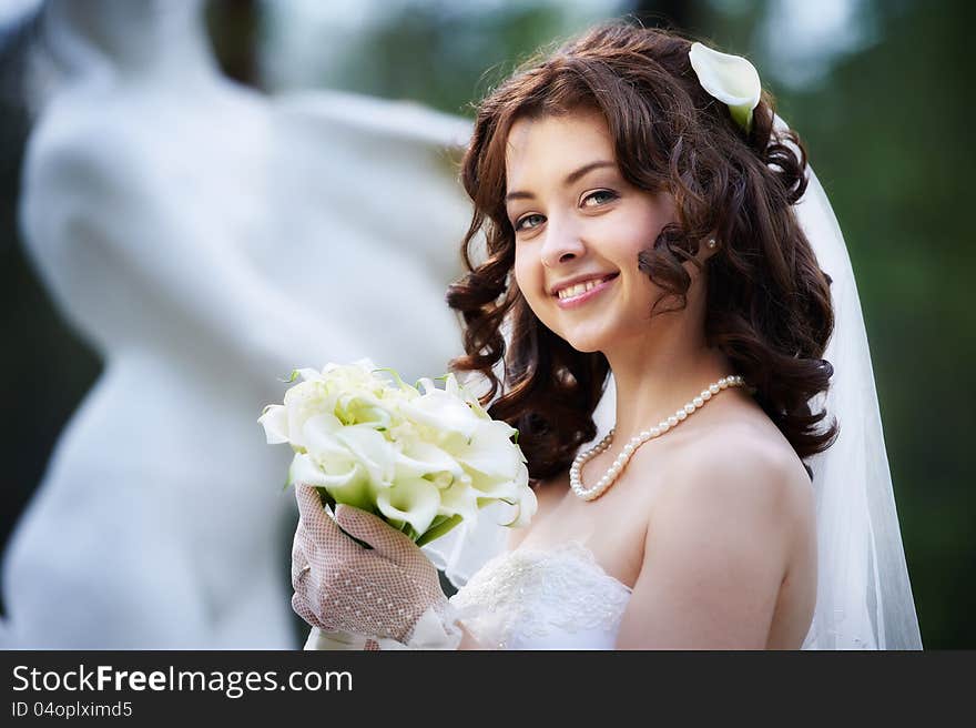 Happy bride with white wedding bouquet on blurred background