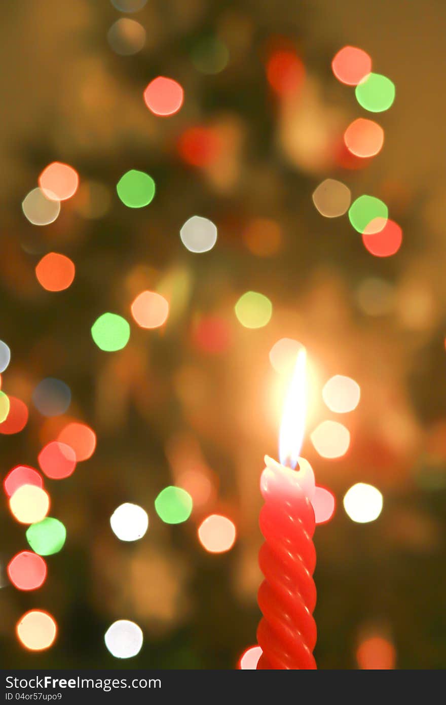 A red Christmas candle with a background of out-of-focus Christmas tree tree lights