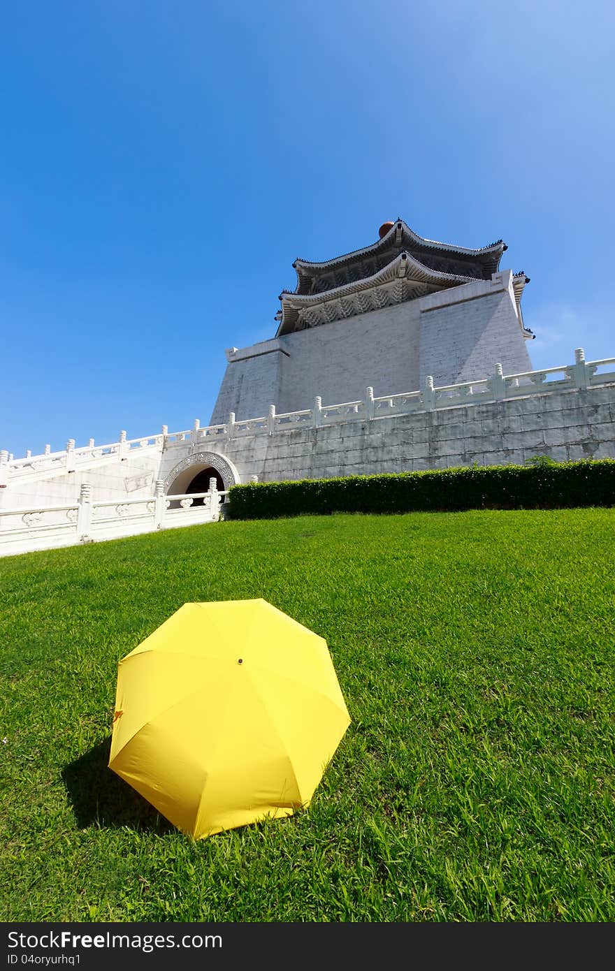 Yellow umbrella on green grass with blue sky