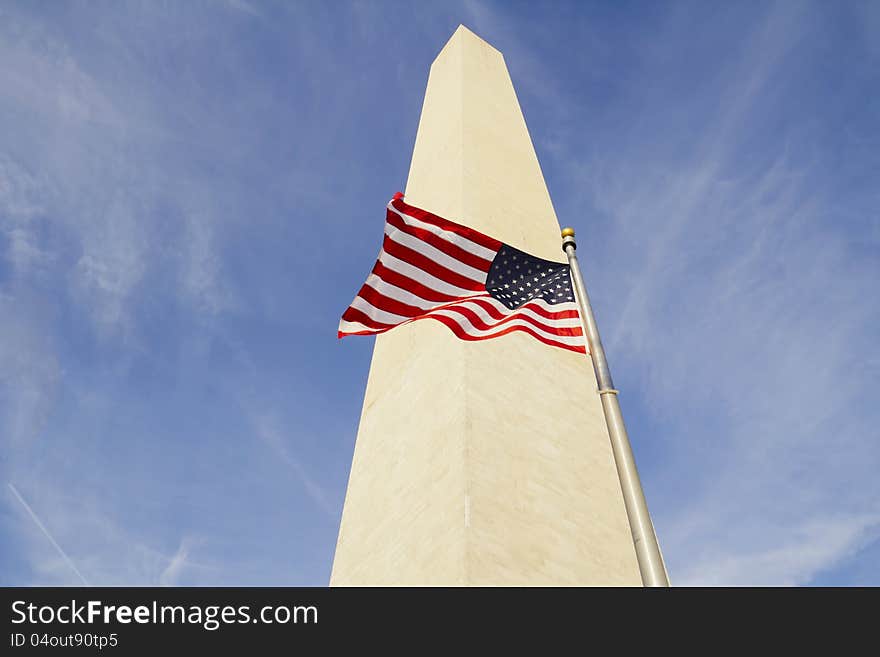 Washington Monument in Washington DC with flapping american flag on a flagpole