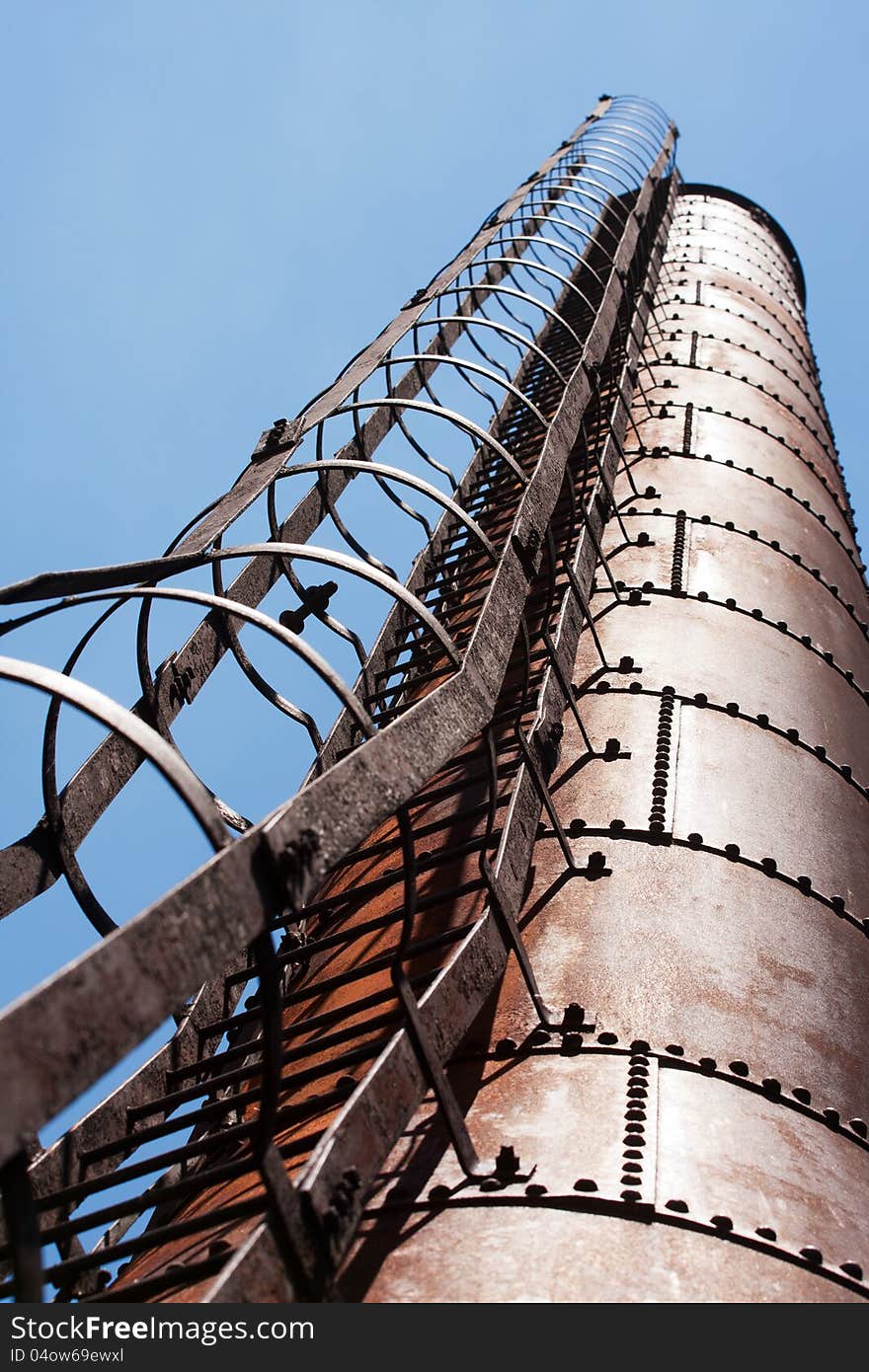 Industrial factory chimney with ladder against blue sky. Industrial factory chimney with ladder against blue sky