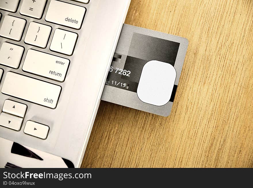 Credit card insert inside laptop on the wooden desk