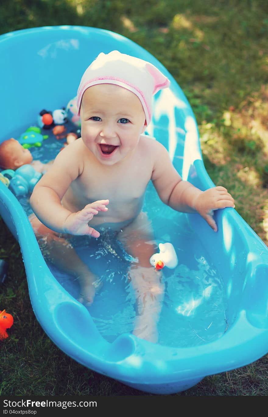 Charming baby having bath in blue tub. Charming baby having bath in blue tub