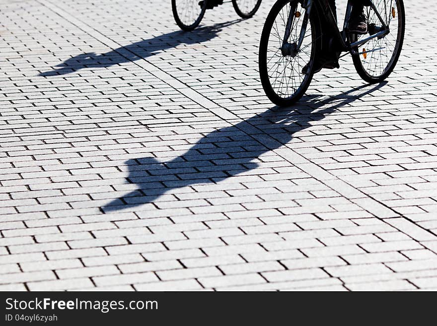 Cyclists cast long shadows on the pavement. Cyclists cast long shadows on the pavement