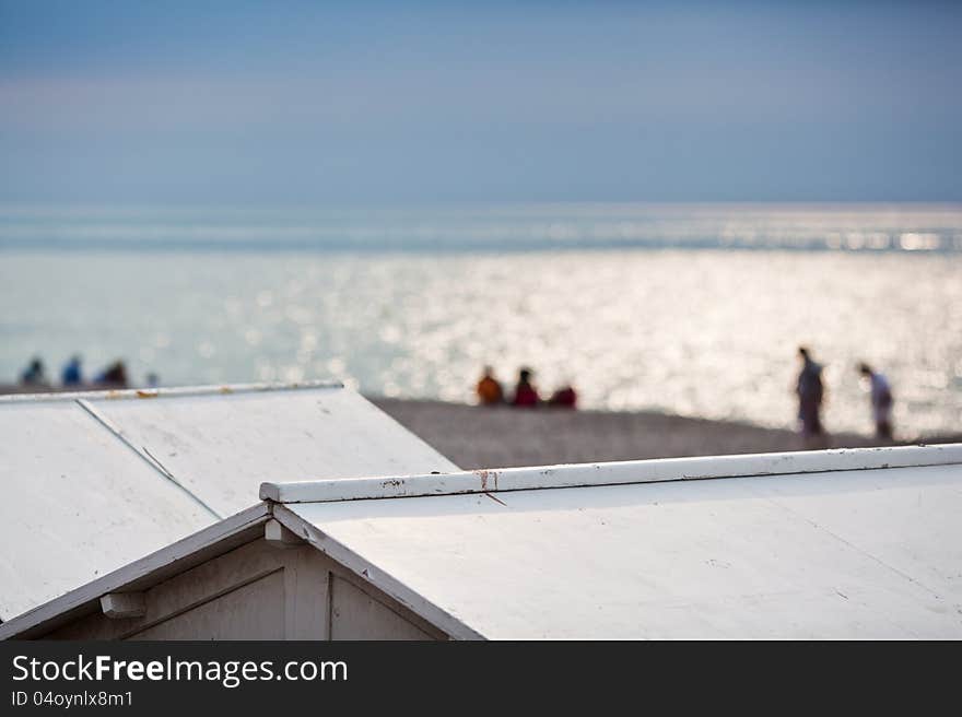 View over beach hut roofs to the blurred people at the beach in Mers-les-Bains, Normandy, France. View over beach hut roofs to the blurred people at the beach in Mers-les-Bains, Normandy, France