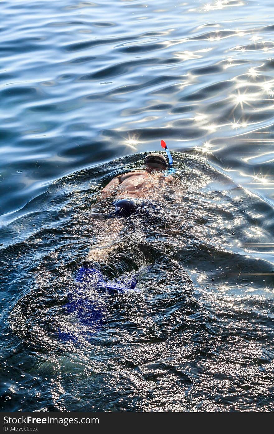 A man with a pipe, a mask and fins floating in the sea. A man with a pipe, a mask and fins floating in the sea