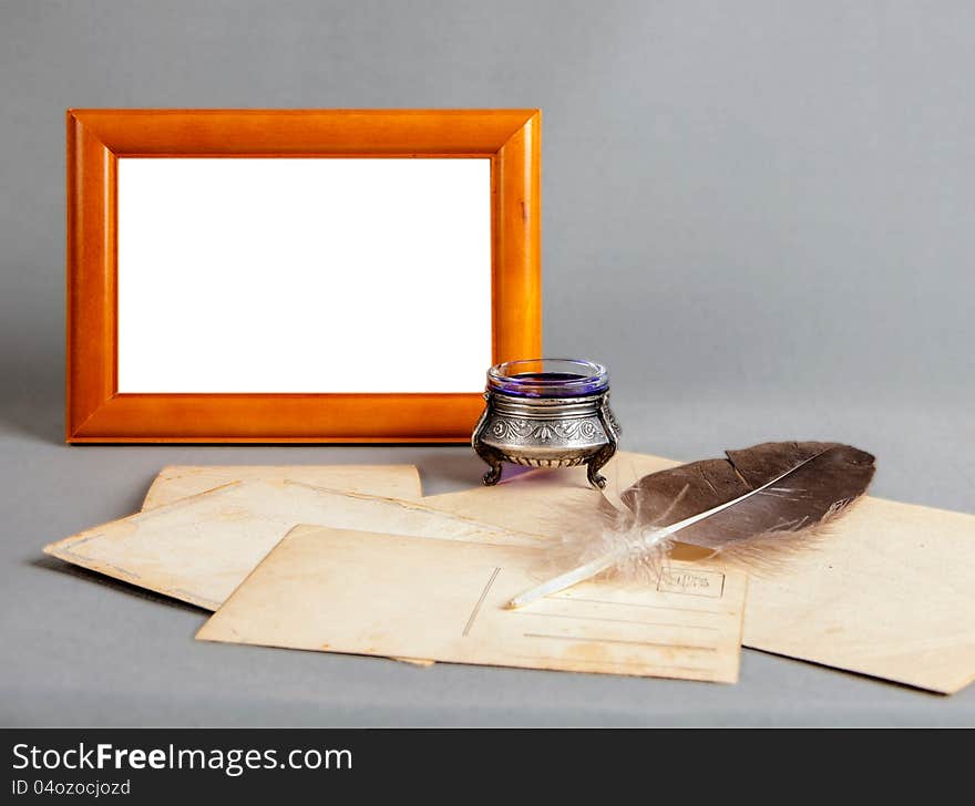 Wooden frame, silver old ink, pen, old postcards on a grey background