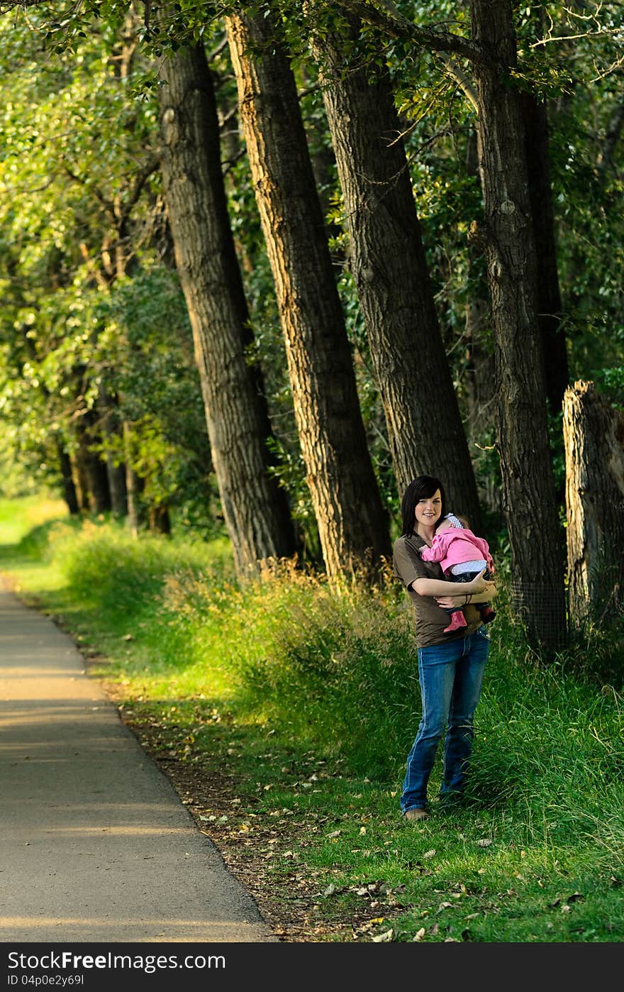 Young mother holding her baby daughter in an outdoor park. Young mother holding her baby daughter in an outdoor park