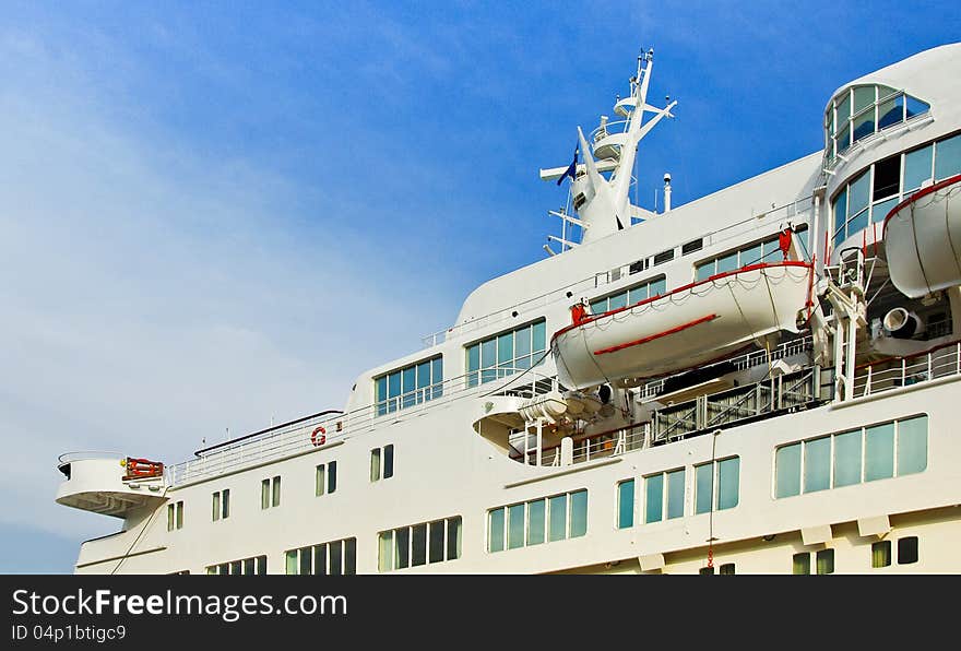 White cruise liner with portholes mooring in the sea port. Luxury cruise ship at blue sky background. Ocean liner with perspective view.