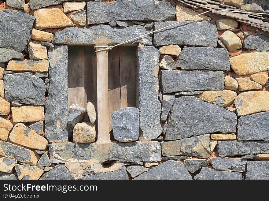 Rough window surrounded by a wall of stones