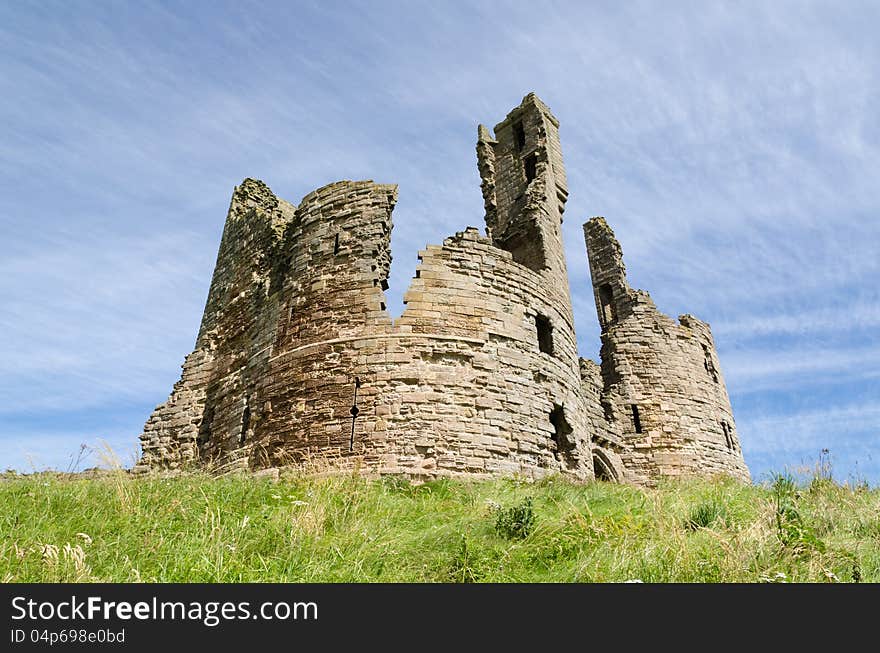 Iconic Dunstanburgh castle ruin built in the 14th century viewed from below the hill close up. Iconic Dunstanburgh castle ruin built in the 14th century viewed from below the hill close up