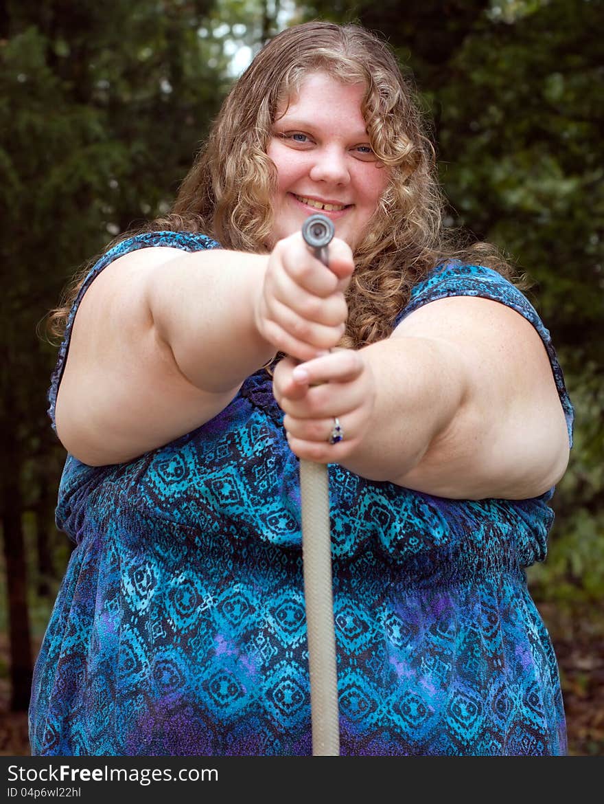 A plus-size young adult female pointing a water hose sprayer. A plus-size young adult female pointing a water hose sprayer.