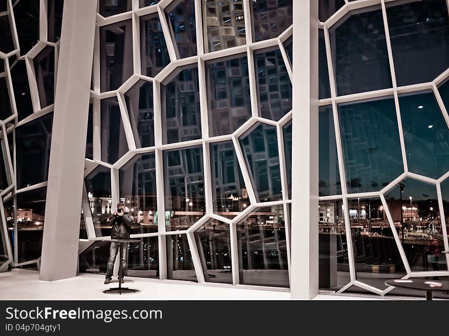 Man taking photo inside of glass house. Reykjavík city is in the background