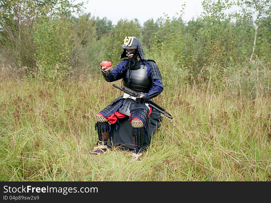 Man dressed in Japanese armor of the XVI century holding pink tea bowl (chawan). Man dressed in Japanese armor of the XVI century holding pink tea bowl (chawan)