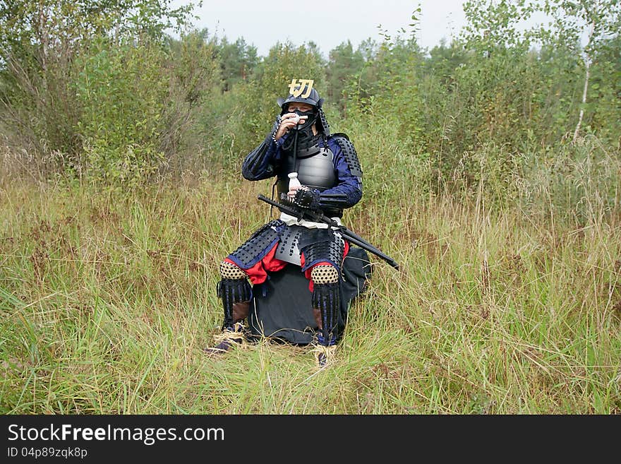 Man dressed in Japanese armor of the XVI century drinking sake from small cup. Man dressed in Japanese armor of the XVI century drinking sake from small cup