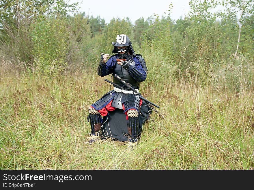 Man dressed in Japanese armor of the XVI century eating from earthen dish using chopsticks. Man dressed in Japanese armor of the XVI century eating from earthen dish using chopsticks