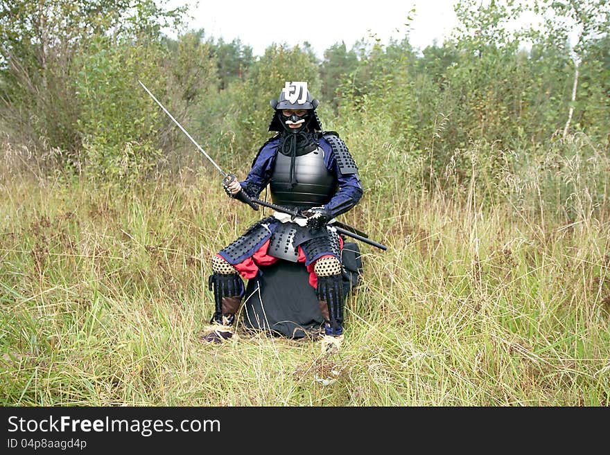 Man dressed in Japanese armor of the XVI century holding long sword katana. Man dressed in Japanese armor of the XVI century holding long sword katana