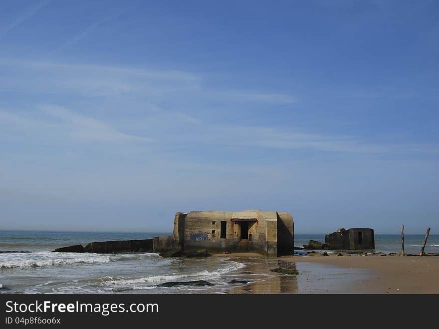 Under a blue sky there are on a French beach two German bunkers from Second World II. Under a blue sky there are on a French beach two German bunkers from Second World II