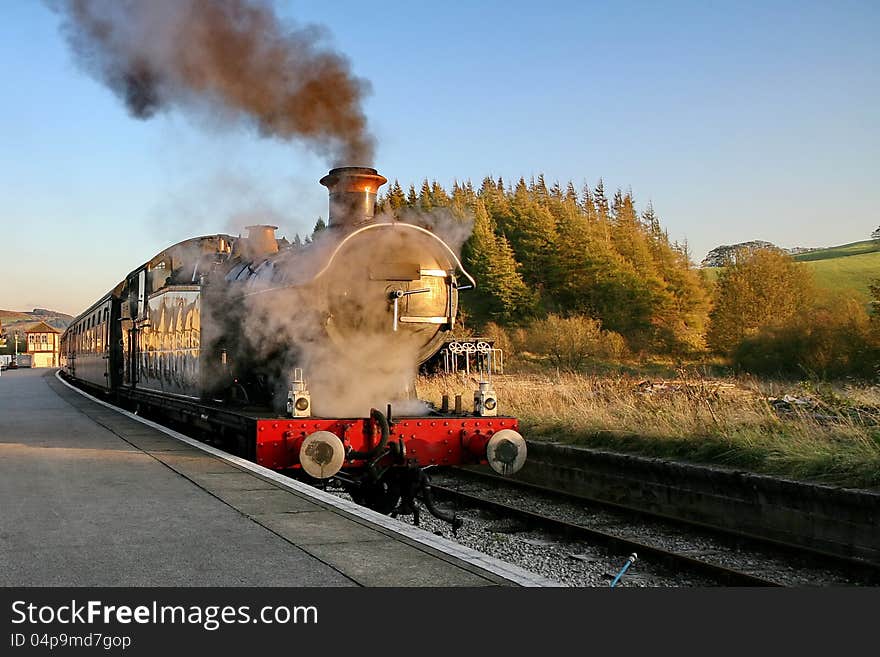 Steam railway engine billows steam and smoke whilst waiting at a station. Steam railway engine billows steam and smoke whilst waiting at a station