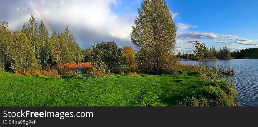 Picturesque autumn landscape with river and bright rainbow over the woodland. Picturesque autumn landscape with river and bright rainbow over the woodland