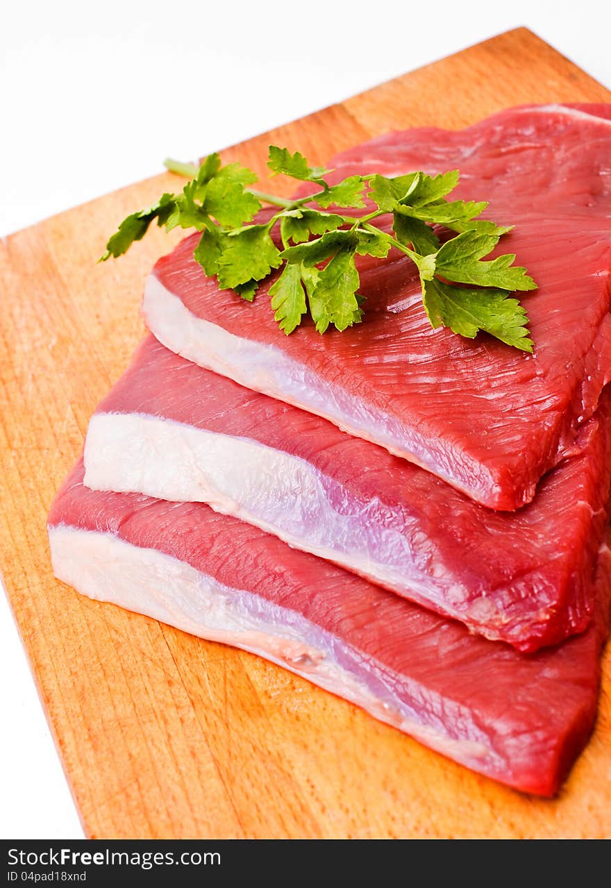 Raw meat slices on board with parsley