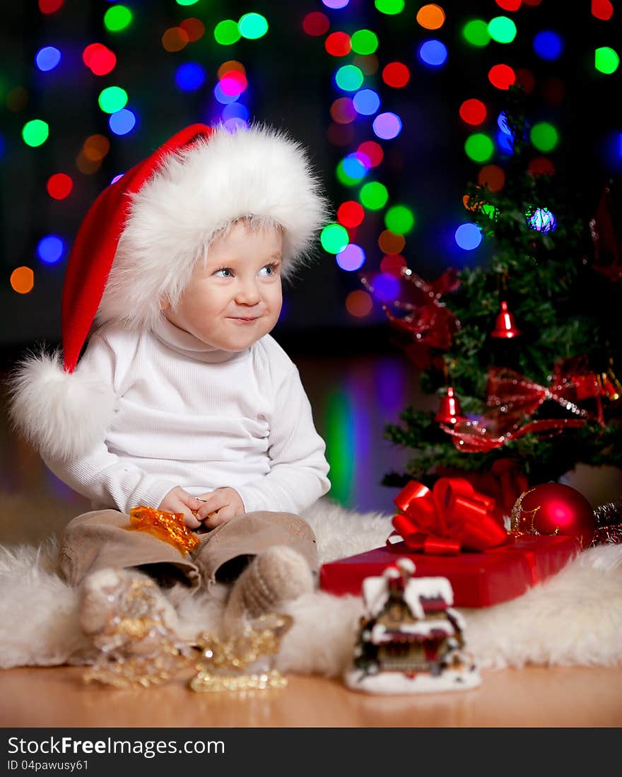 Funny baby in Santa Claus hat on bright festive background. Funny baby in Santa Claus hat on bright festive background