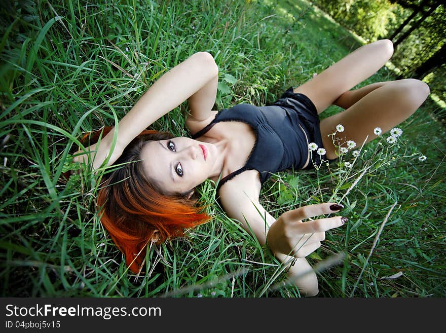 Portrait of pretty redhead girl in the grass