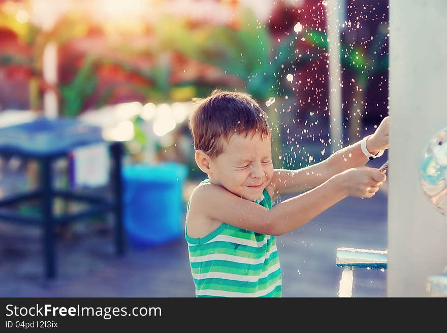 boy having fun with pool fountain shot during summer time. boy having fun with pool fountain shot during summer time