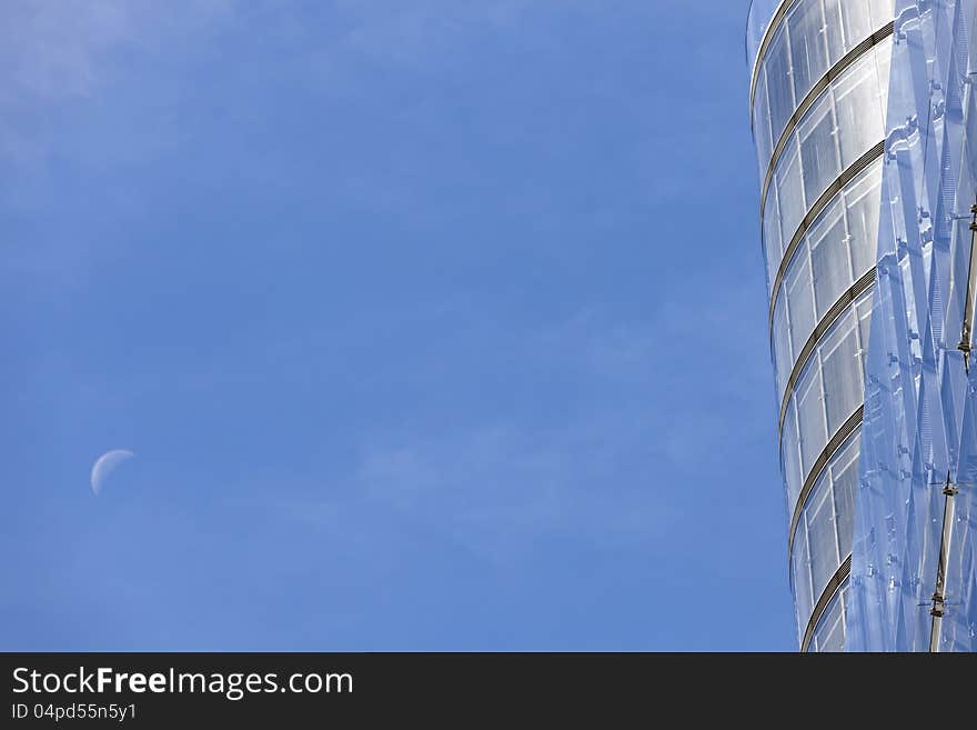 Modern office building with rising moon in abstract composition and much copy space.