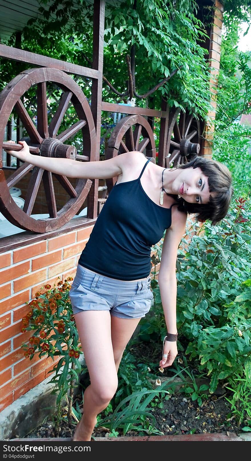 Beautiful girl near the gazebo with wooden wheels. Beautiful girl near the gazebo with wooden wheels