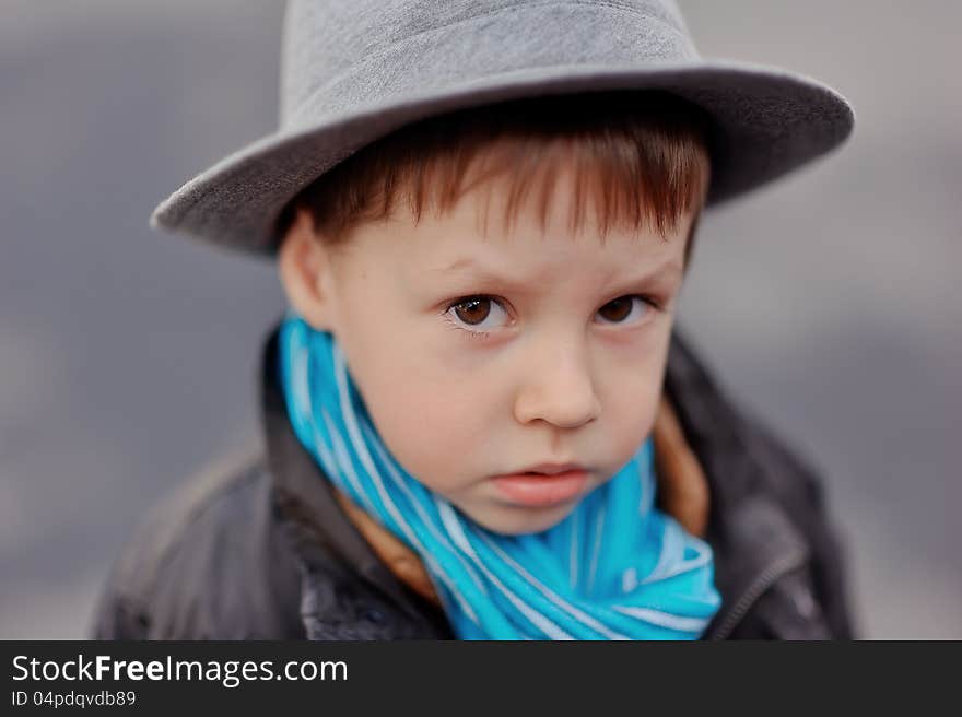 Portrait of a boy in an elegant gray hat and blue scarf. Portrait of a boy in an elegant gray hat and blue scarf