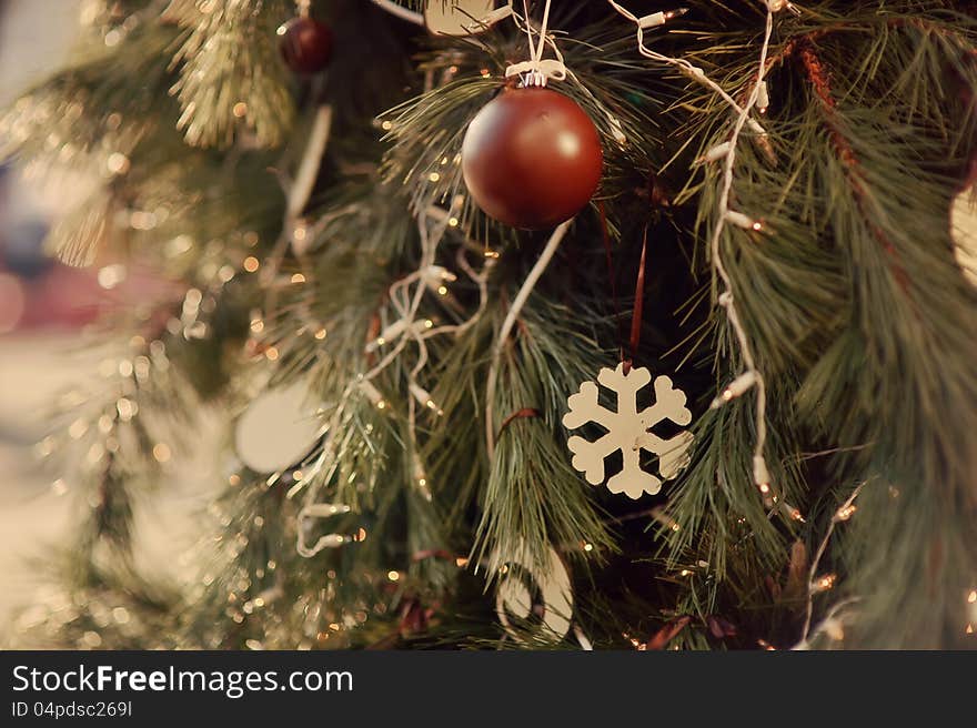 The child decorates a green New Year tree with color toys. The child decorates a green New Year tree with color toys