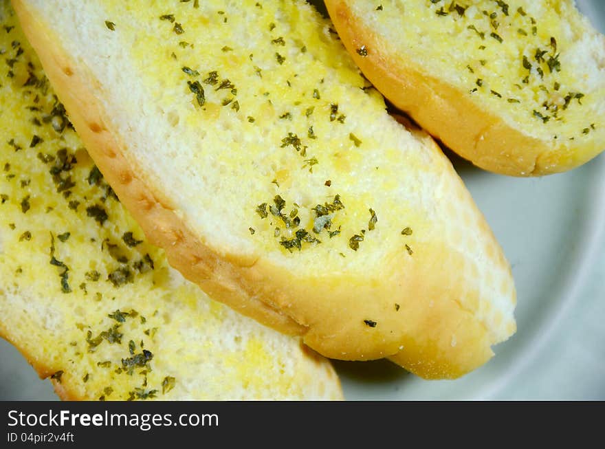 Sliced bread bun spread with butter, garlic and herb. Sliced bread bun spread with butter, garlic and herb.