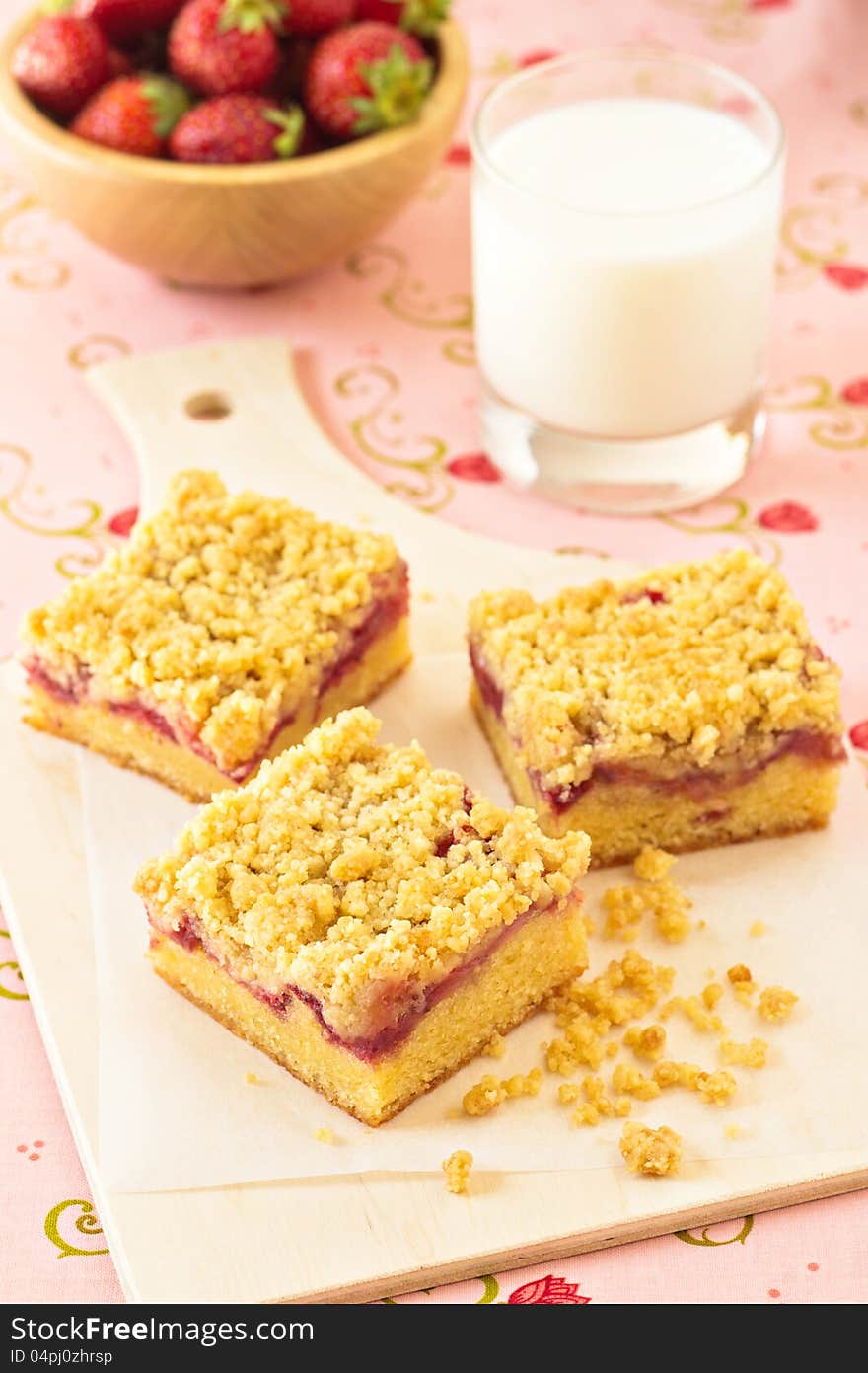 Strawberry crumb cake with a glass of milk and a bowl of fresh strawberries