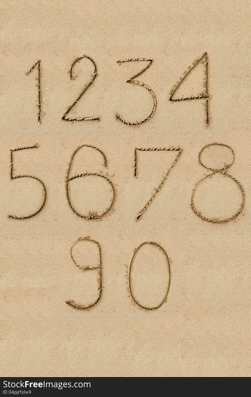 Numbers one to zero written on sand