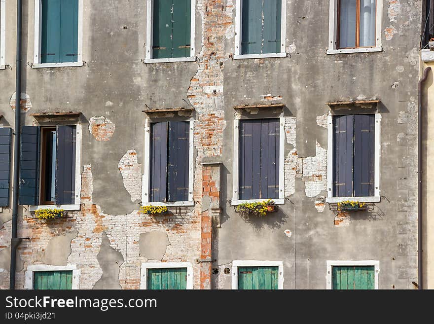 Facade fragment of an old building with windows and the peeled-off facing plaster